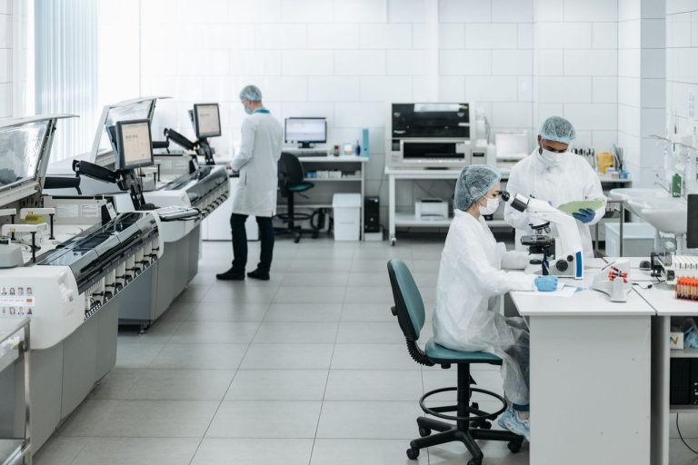 Pesquisadores usando jalecos realizam experimentos com equipamentos avançados em um laboratório.