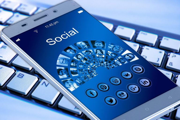 Visibilidade de conteúdo político vira foco de decisão do TSE sobre Meta Smartphone sobre um teclado, cercado por elementos gráficos associados a aplicativos, internet e redes sociais.
