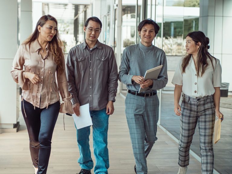 Desemprego cai para 5,3% e Brasil registra recorde de 103,5 milhões de ocupados Quatro trabalhadores caminham e conversam em um corredor moderno de escritório, carregando documentos.